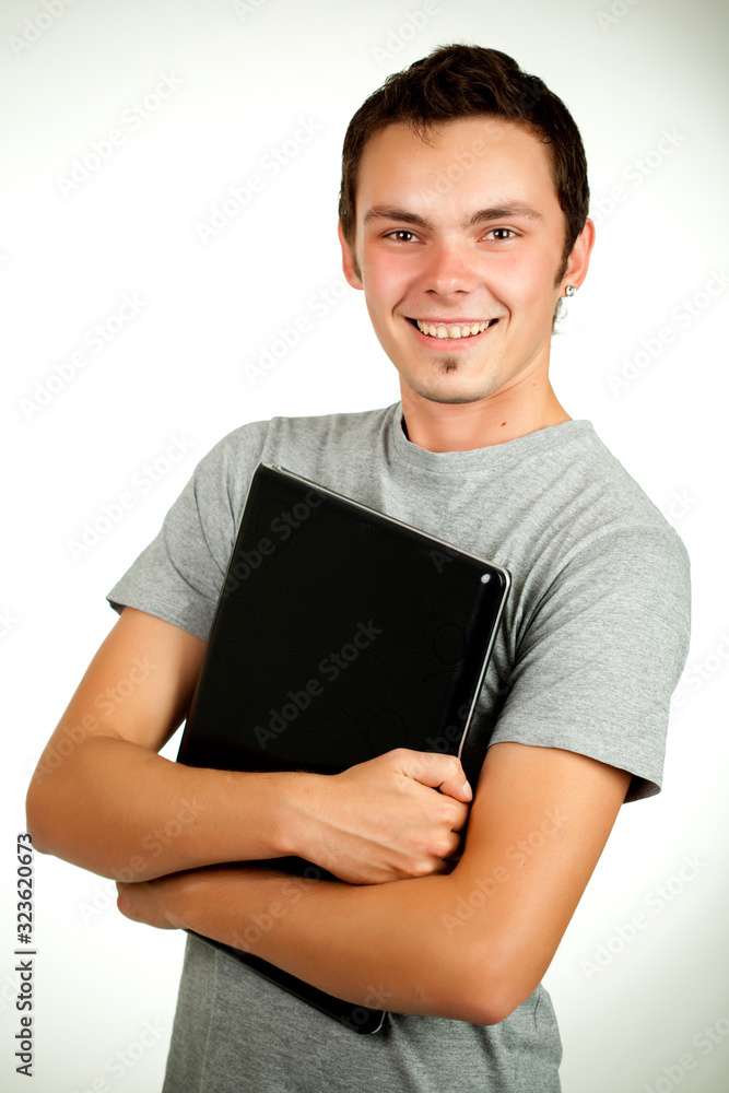 Portrait of a positive pretty young student guy in casual wear typing text on a laptop on a white background. Concept Student Studying Freelancing and Online Shopping. Advertising space Portrait of a positive pretty young student guy in casual wear typing text on a laptop on a white background. Concept Student Studying Freelancing and Online Shopping. Advertising space