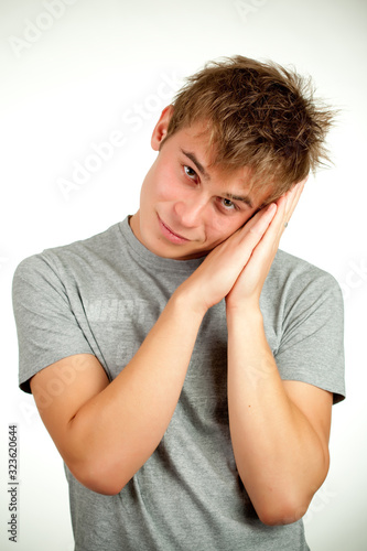 Portrait of a Caucasian young positive guy in a gray shirt and jeans posing on a gray background. Concept of a successful young student or novice employee. Advertising space