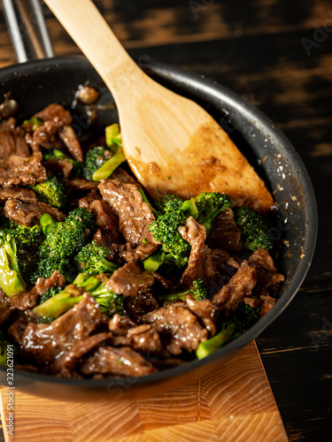 Beef meat and broccoli vegetable cooking in pan close up, selective focus. Traditional food recipe.