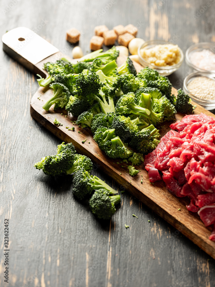Fresh healthy broccoli vegetables and raw meat cutting on wooden desk. Close up. Cooking recipe concept.