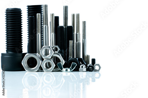 Metal bolts and nuts on white background. Fasteners equipment. Hardware tools. Stud bolt, hex nuts, and hex head bolts in workshop. Threaded fastener use in automotive engineering. Hexagonal bolt. photo