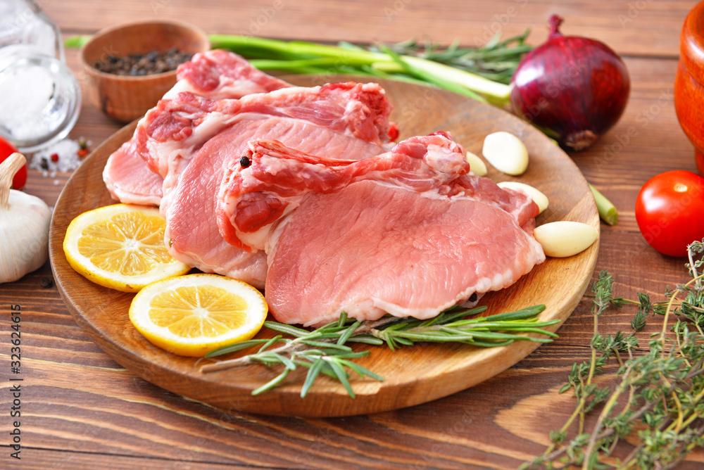 Plate with raw pork meat on wooden background Plate with raw pork meat on wooden background