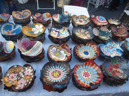 Asian souvenirs for tourists. Traditional Thai, Asian and Oriental crafts - making small bowls of coconut shells, decorating them with various thematic images. Assortment of goods of street market.