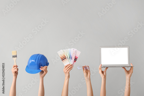 Many hands with architect's supplies and laptop on grey background