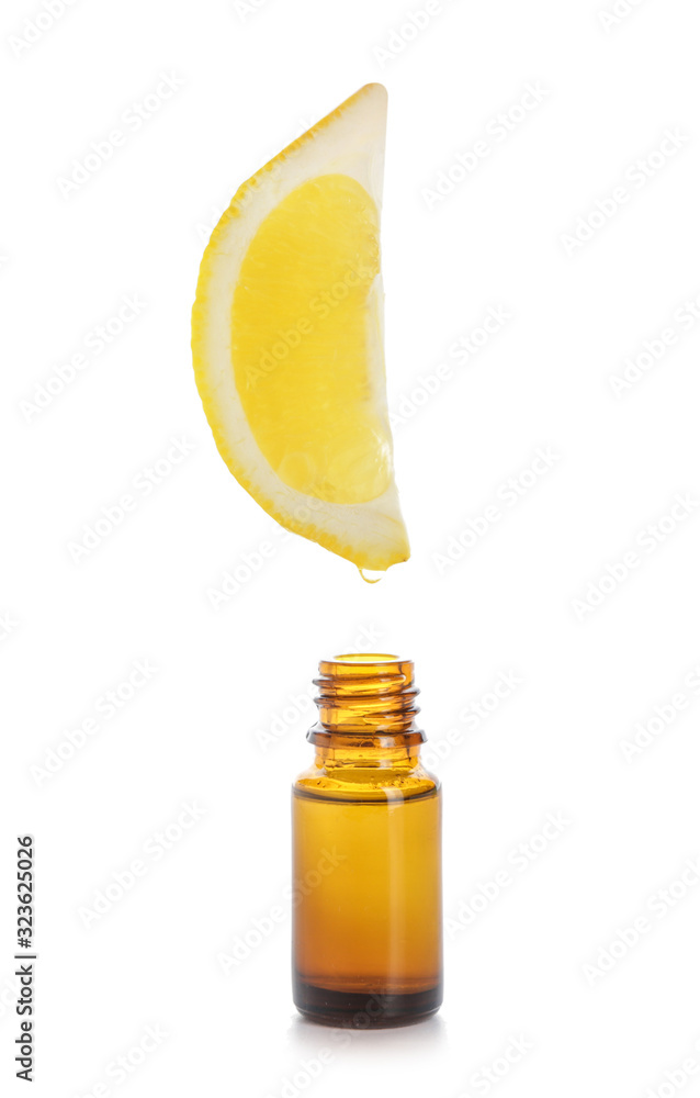 Essential oil dripping from lemon slice into bottle on white background Essential oil dripping from lemon slice into bottle on white background