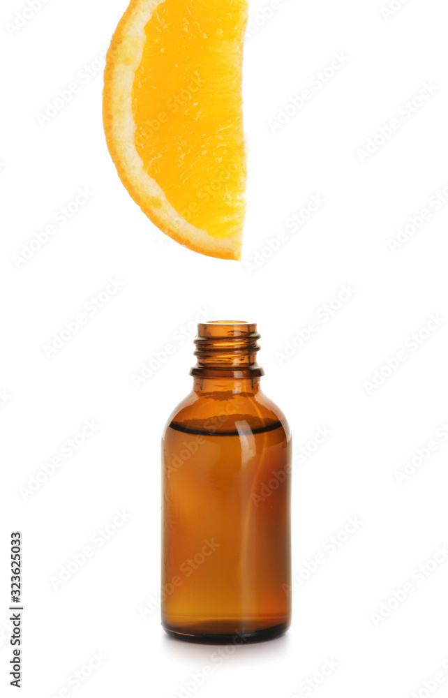 Essential oil dripping from orange slice into bottle on white background Essential oil dripping from orange slice into bottle on white background