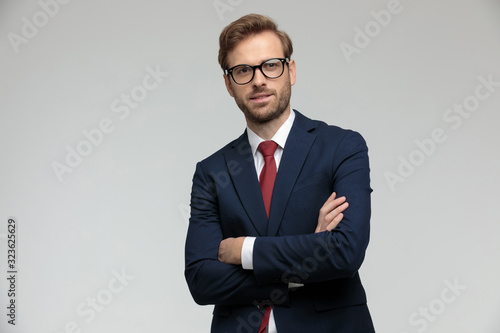 businessman standing with arms crossed and looking ahead satisfied