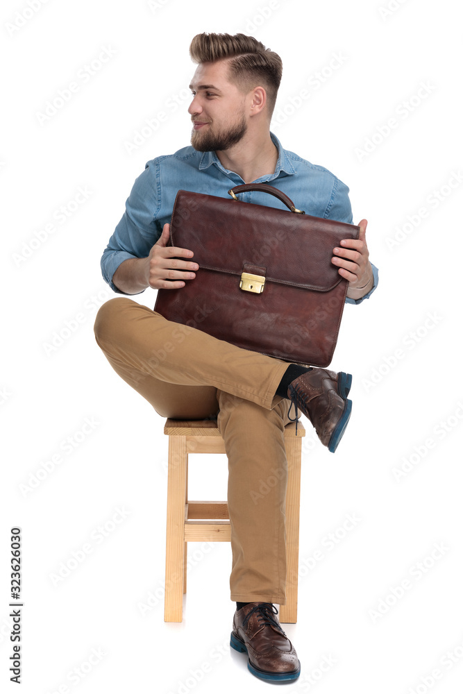 smiling young guy holding suitcase and looking to side smiling young guy holding suitcase and looking to side