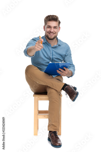 casual young man pointing finger and holding clipboard