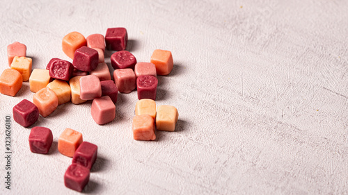 Little chewing candies on a grey background. Colours of candies: orange, rose and purple. 