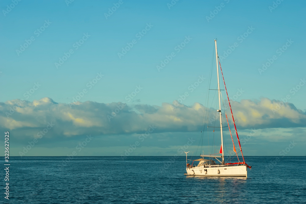 A small boat bobs on the surface of a calm sea. Dawn over the ocean. Colorful sky and calm ocean.