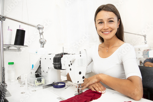 Lovely female fashion designer using sewing machine