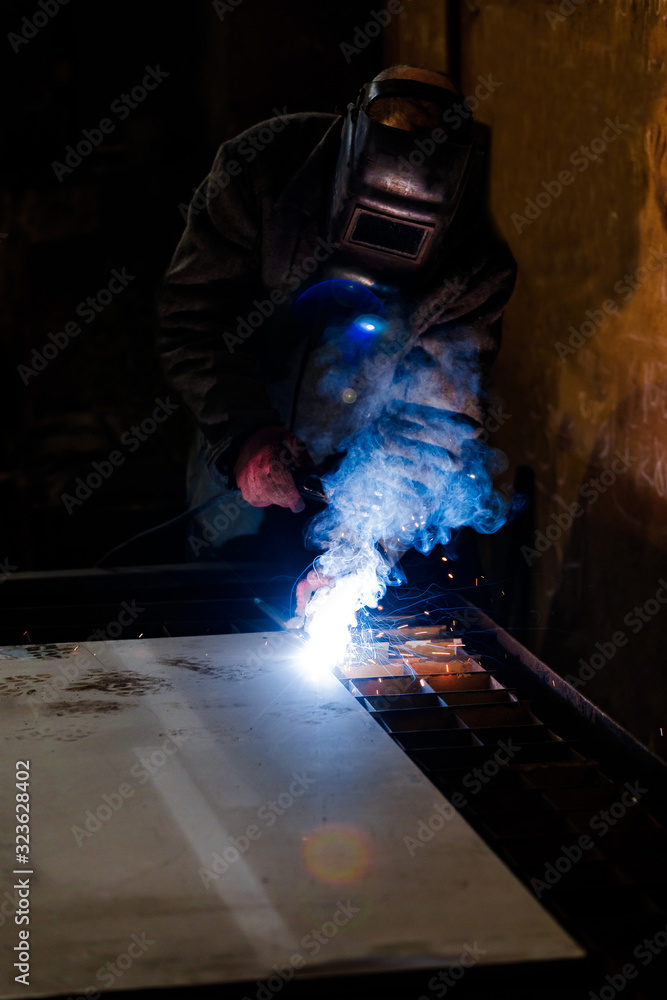 worker in protective uniform and mask welding metal. man using electric welding machine worker in protective uniform and mask welding metal. man using electric welding machine