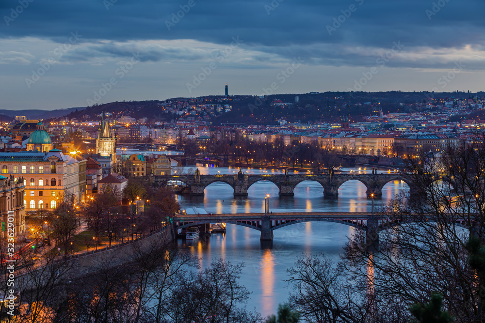 Prague, Czech Republic - Panoramic skyline of the city of Prague at dusk with blue clouds. Included the illuminated famous Charles Bridge, St. Francis Of Assisi Church and River Vltava at wintertime