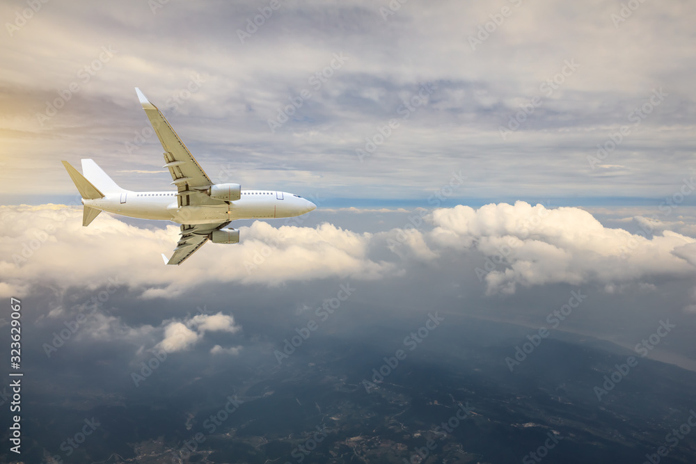 Fototapeta premium Airplane flying at high altitude over green mountains and sky at sunrise