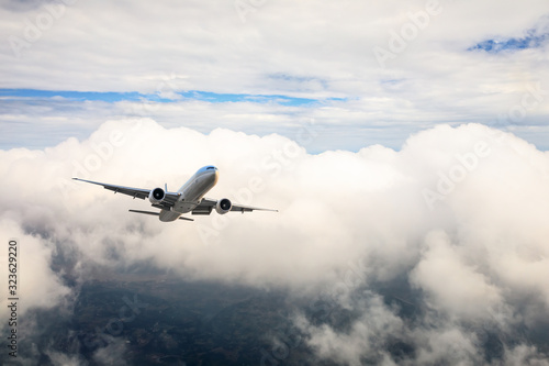 Airplane flying at high altitude over green mountains and sky at sunrise