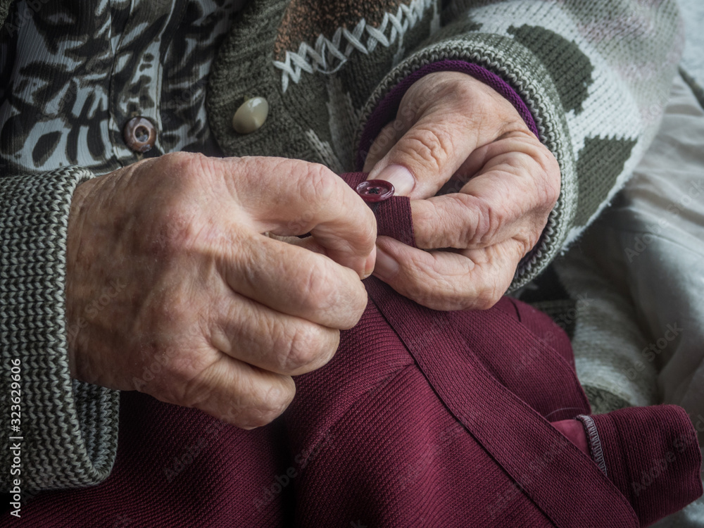 Older woman's hands sewing a button