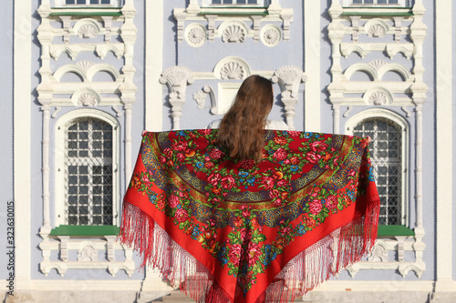 Tourist girl in ancient red Pavlovo Posad shawl and architecture of Tula city, Russia. Russian traditional national folk style in architectural fashion. Assumption (Uspensky) Cathedral in Tula Kremlin photo