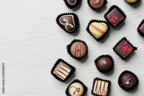 Obraz na plátně Top view of various chocolate pralines on wooden background