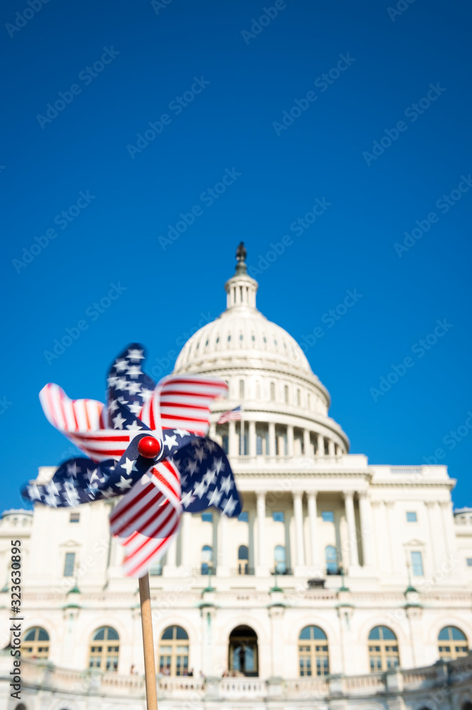 Motion blur view of American flag pinwheel spinning in sunny blue sky in front of the US Capitol building in Washington DC, USA