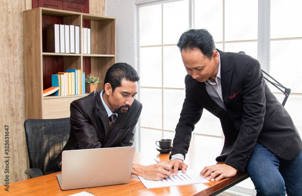 Young executive business man discussing to partner or colleague point investment strategy presentation on technology laptop, Asian mature beard man suit solve problem with employee in workplace Young executive business man discussing to partner or colleague point investment strategy presentation on technology laptop, Asian mature beard man suit solve problem with employee in workplace