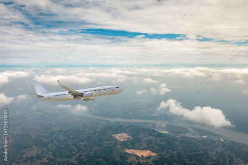 Airplane flying at high altitude over green mountains and sky at sunrise