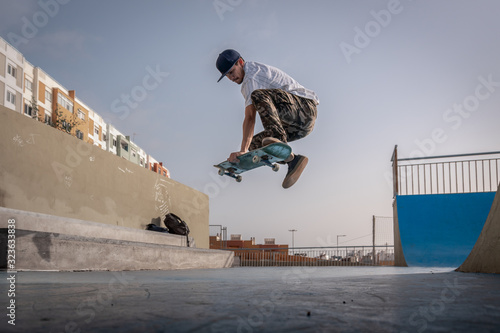 El joven patinador hace un truco llamado boneless  en un parque de skate photo