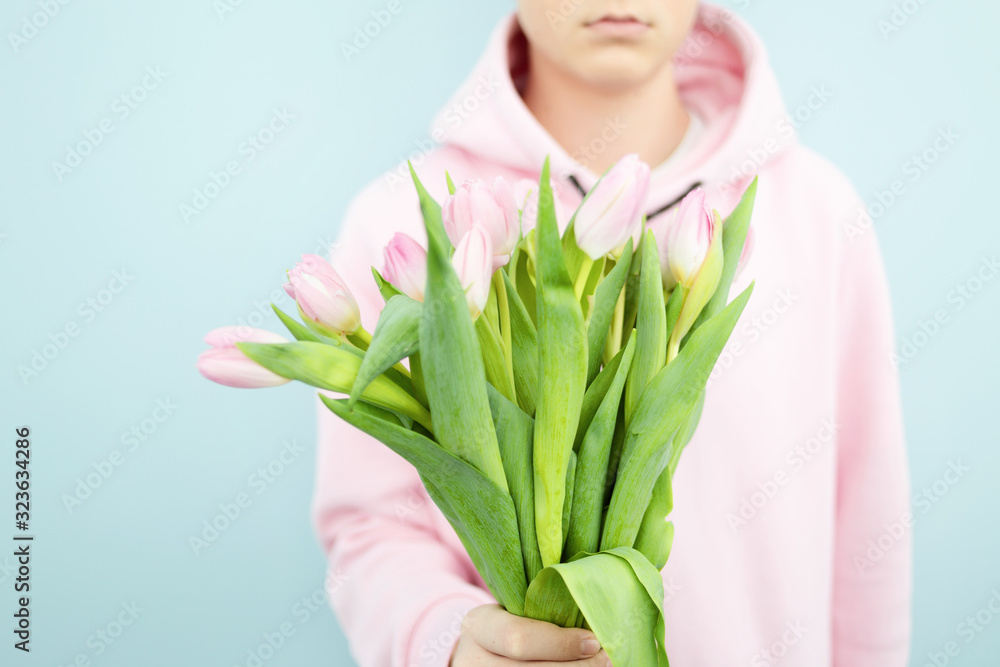 March 8 or Valentine's Day, A bouquet of flowers in the hands of a boy, surprise, gift, behind. March 8 or Valentine's Day, A bouquet of flowers in the hands of a boy, surprise, gift, behind.