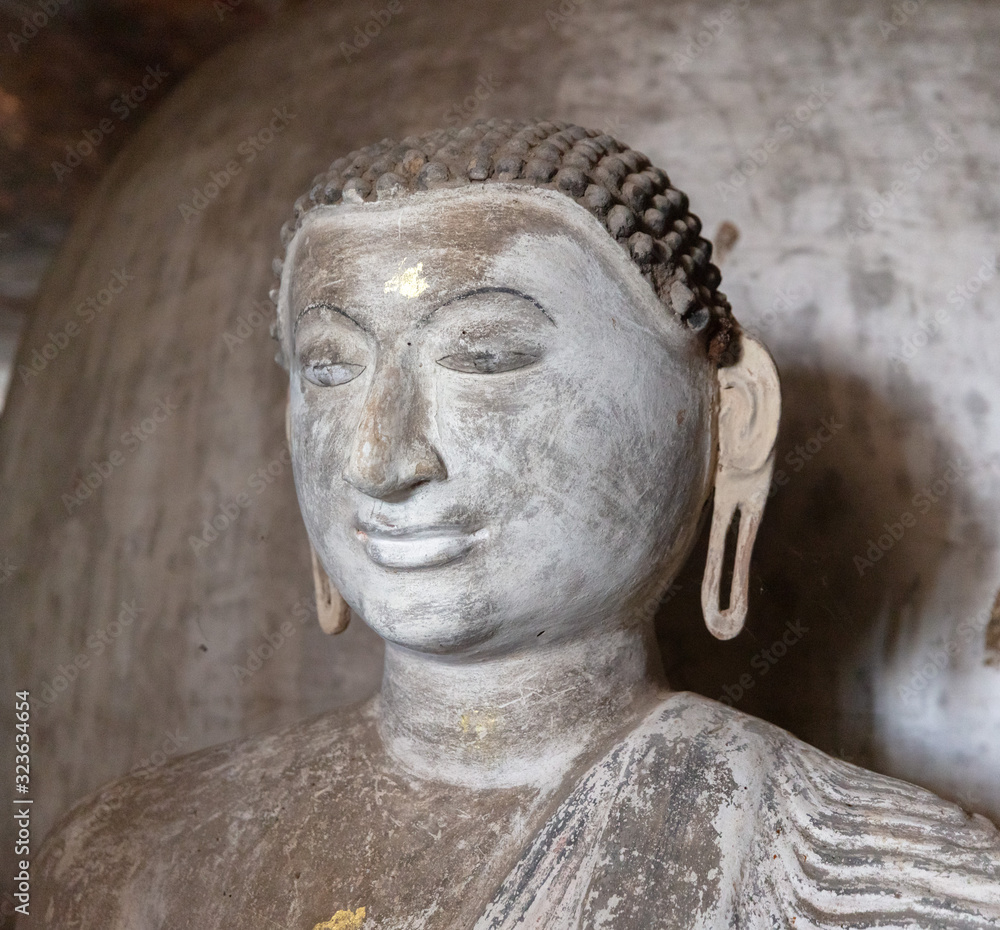 Smiling Buddha portrait insides in ancient Buddhist complex in Dambulla cave temple in Sri Lanka.