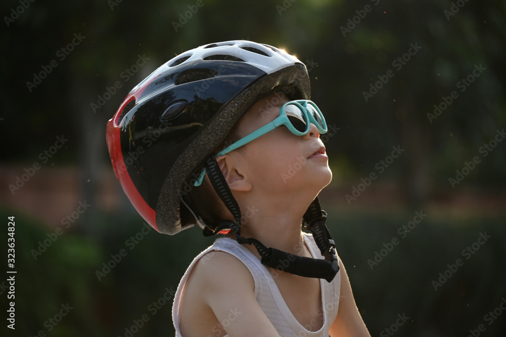 happy cute boy wear sunglasses and sport helmet playing balance bike exercise in the morning day happy cute boy wear sunglasses and sport helmet playing balance bike exercise in the morning day