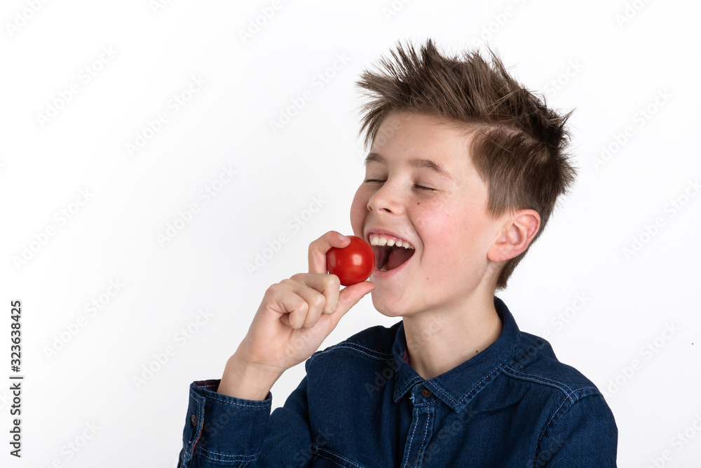 fröhlicher Junge genießt reife Tomate, europäisch, freigestellt Hintergrund weiß fröhlicher Junge genießt reife Tomate, europäisch, freigestellt Hintergrund weiß