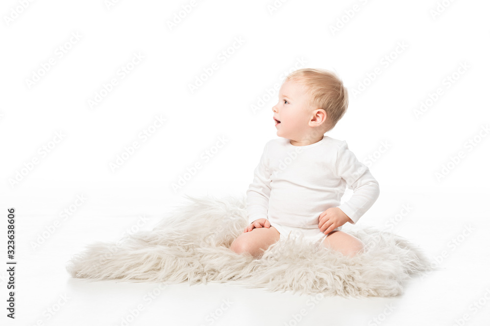 Cute kid looking away with open mouth and sitting on fur on white background Cute kid looking away with open mouth and sitting on fur on white background