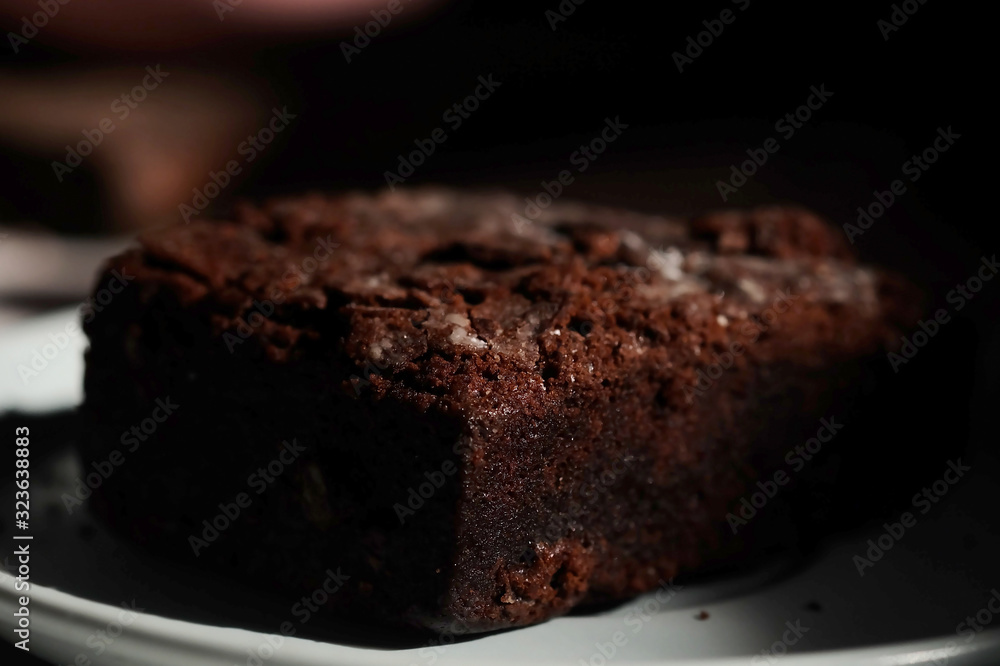 Homemade chocolate cake in white dish and sunlight and space for write wording, unhealthy sweet caused dangerous chronic illness such as diabetes, popular sweet sold in restaurant.