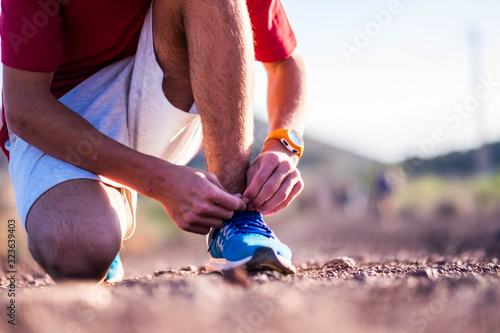 close up annd portrait of man taking a break after running or jogging to fix his shoe to no fall photo