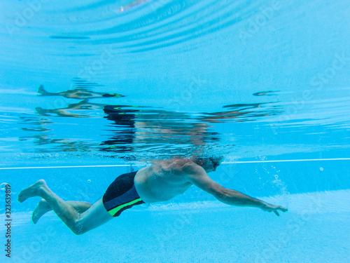 one mature man swimming alone at the pool and doing exercise to e healthy and fitness man - senior inside a swimming pool - underwater view