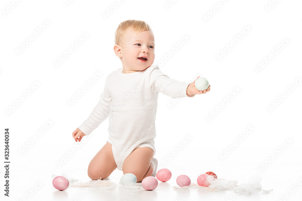 Child next to easter eggs and feathers on white background Child next to easter eggs and feathers on white background