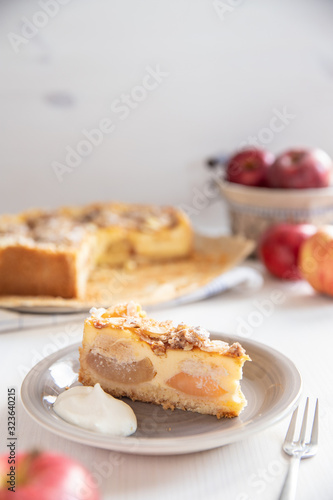 Bratapfelkuchen mit Äpfeln und Mandelblättchen auf hellem weißen Holzgrund
