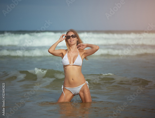 Young slim beautiful woman stay and posing in the sea or ocean waves