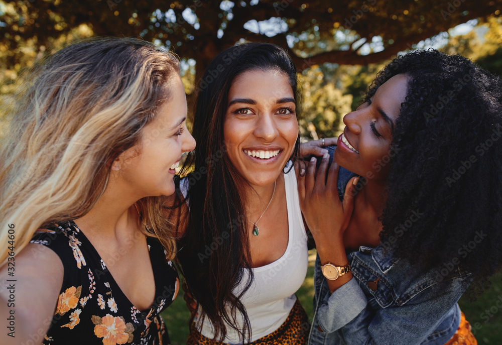 Obraz premium Excited young group of women posing between female charming friends in trendy clothes taking selfie - young girls taking a selfie in a park on a sunny day