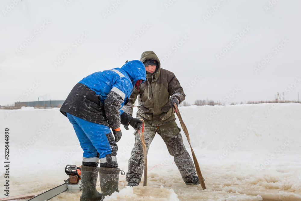 Slingers in protective overalls start a sling under the ice block Slingers in protective overalls start a sling under the ice block