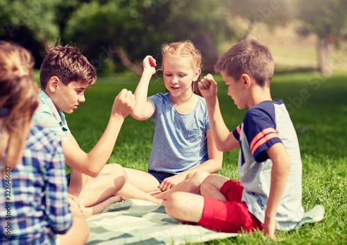 summer holidays, entertainment, childhood, leisure and people concept - group of happy pre-teen kids playing rock-paper-scissors game in park © Syda Productions