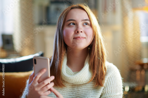 Canvas Print smiling modern teenage girl checking social media on smartphone