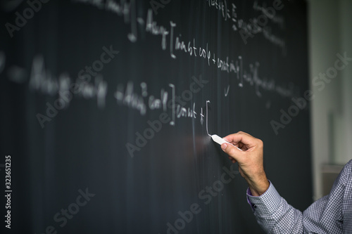 Foto Math teacher by the blackboard during mathclass - detail of the hand with chalk