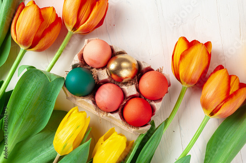 Painted Easter eggs in an eggbox with fresh tulips close up photo