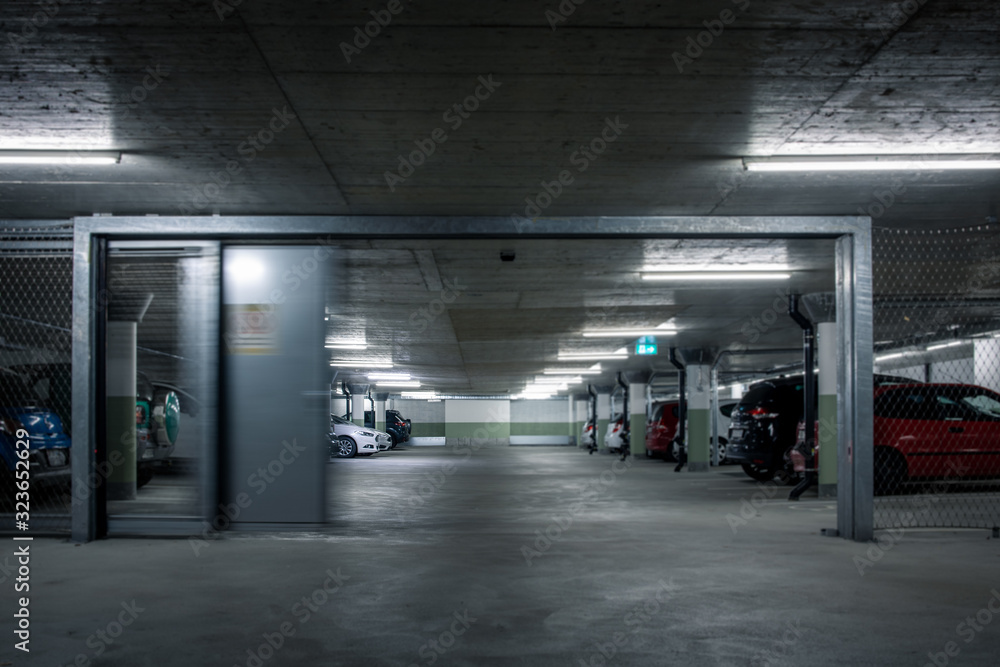 Gated underground parking. Cars parked in a garage with no people. Many cars in parking garage interior. Underground parking with cars (color toned image)