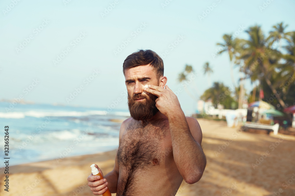 Handsome Man with beard, In Sunglasses Sunbathing With Sunscreen Lotion
