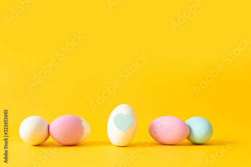 Happy easter background. Decorated white, pink and blue eggs on a yellow background.