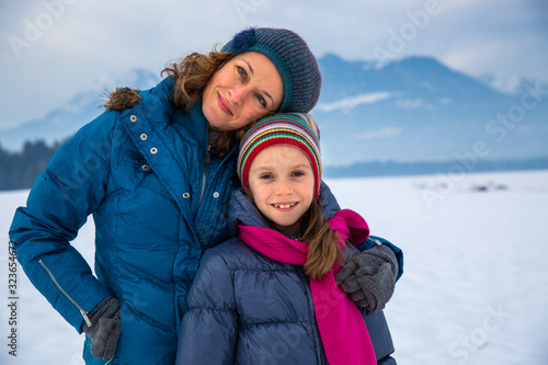 Mother hugging her daughter in snowy landscape