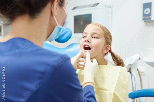 Little cute girl showing a dentist her teeth.