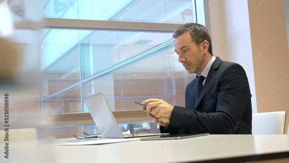 Businessman in modern office talking on phone Businessman in modern office talking on phone